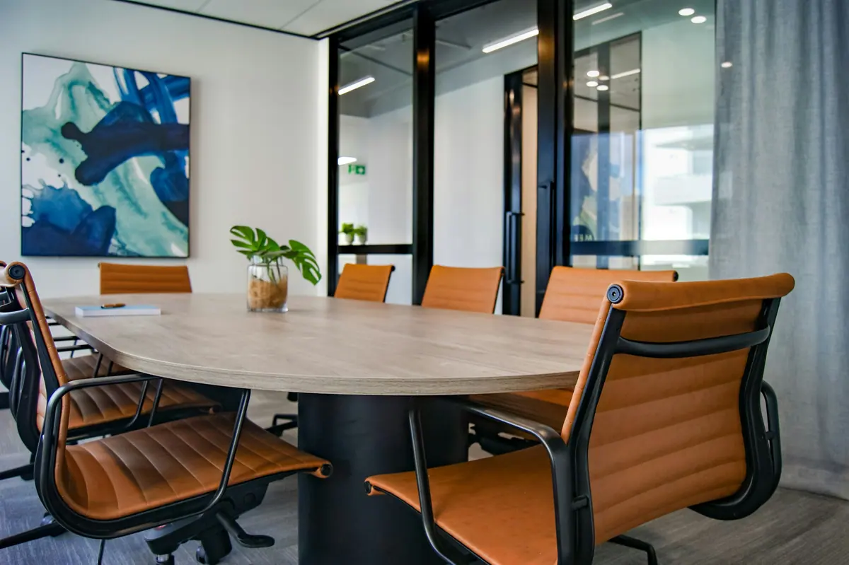 Sala de reunião com mesa em madeira e cadeiras em couro